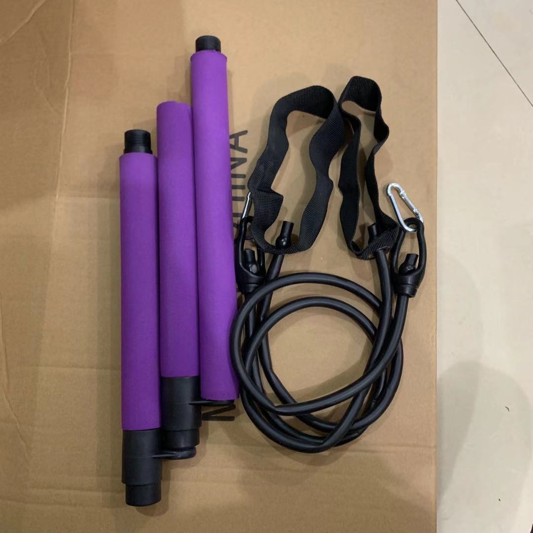 třípólová Pilates cvičební tyč s fialovými rukojeťmi a popruhy pro cvičení.