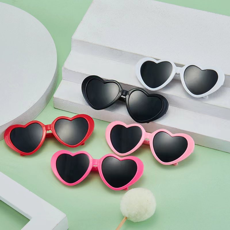 Doll sunglasses for pets v různých barvách na pozadí geometrických tvarů.